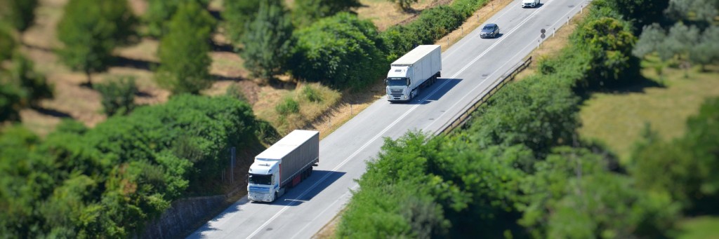 White articulated trucks on a multi-lane highway, representing long-haul commercial haulage