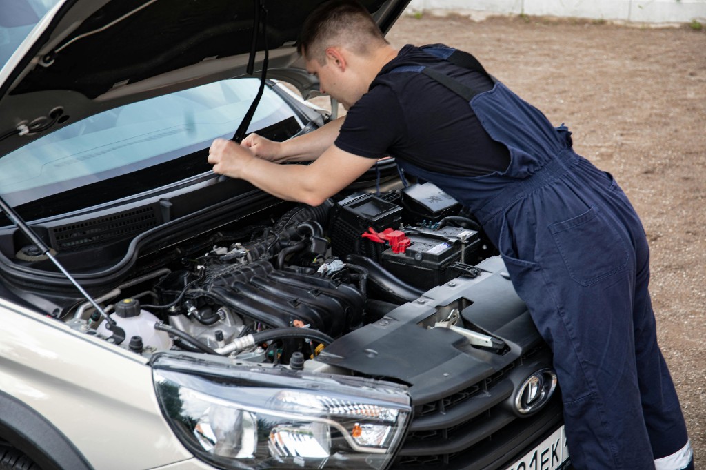 Mechanic carrying out inspection and repair under the bonnet of a vehicle in the workshop