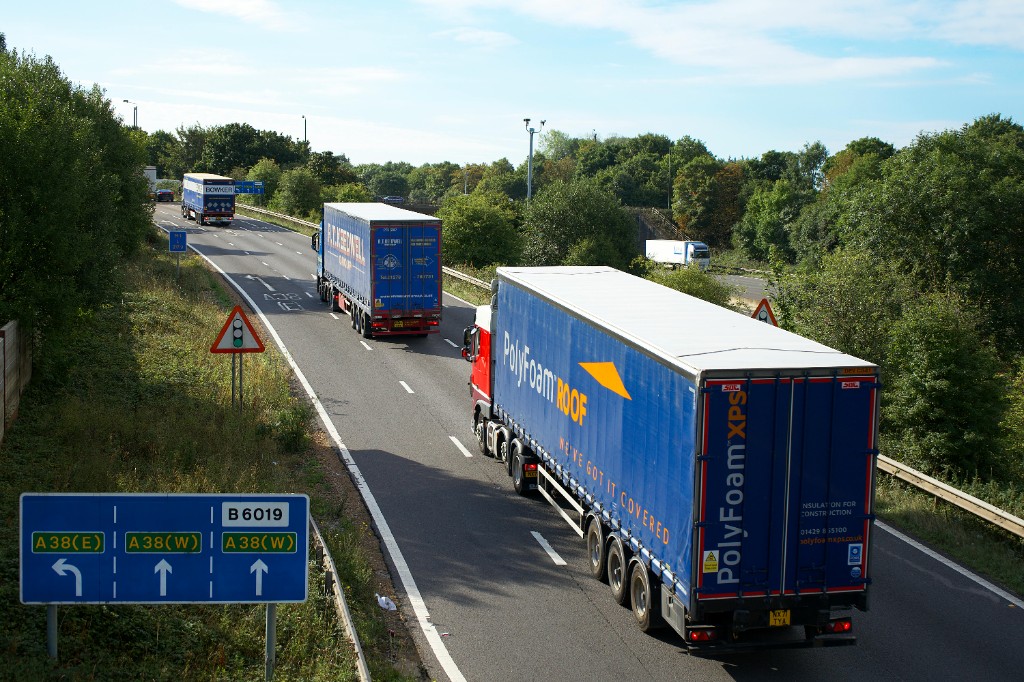 HGVs and curtain-sided trucks on a sunny UK dual carriageway